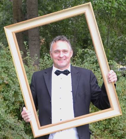 Peter Apelt im Anzug mit goldenem Bilderrahmen
